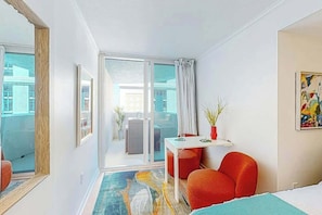A hotel room with a bed, a red armchair, a small table, a potted plant, and a sliding glass door leading to an outdoor area. - Club Wyndham Unit 521 (North Myrtle Beach)