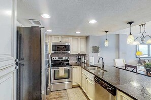 A modern kitchen with stainless steel appliances, a marble countertop, and pendant lighting. - Shoreham Towers Unit 3-B (North Myrtle Beach)