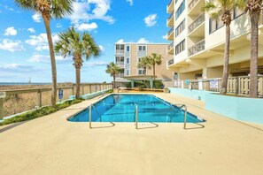 A swimming pool with a clear view of a multi-story building in the background. - Shoreham Towers Unit 3-B (North Myrtle Beach)