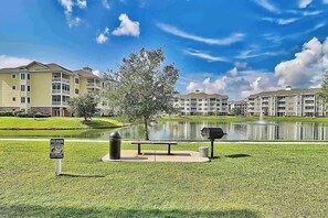 A lakeside park with a picnic area, trash bins, and a sign indicating a dog waste area. - Lakefront Waterview Retreat (Myrtle Beach)
