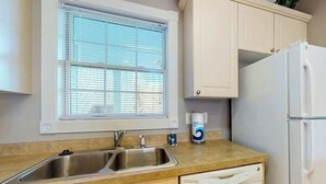 Una cocina con un lavamanos doble, lavavajillas y refrigerador.
