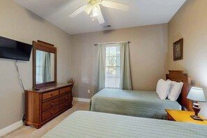 A bedroom with two beds, a dresser, a television, a ceiling fan, and a window with curtains. - Lakefront Waterview Retreat (Myrtle Beach)