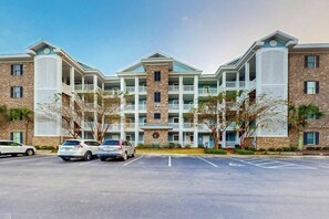 A multi-story hotel with a central courtyard, parking lot, and a brick facade. - Lakefront Waterview Retreat (Myrtle Beach)