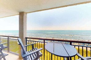 Ein Balkon mit Blick auf den Strand, inklusive Tisch und Stühlen.