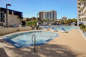 A hotel pool area with lounge chairs and a clear sky. - Sunny and Ready Retreat (Myrtle Beach)