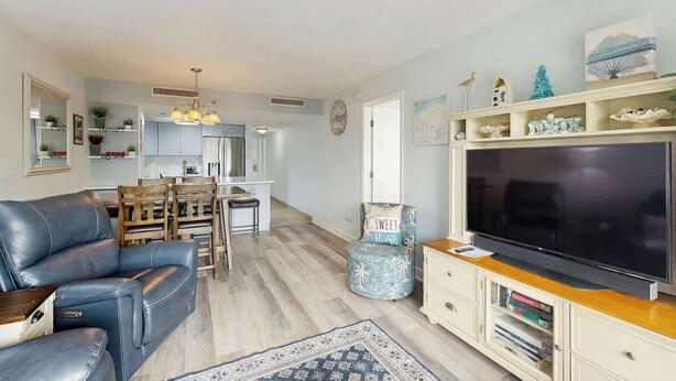 Een woonkamer met een bank, televisie en een eethoek met stoelen en een tafel.