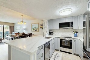 A modern kitchen with a large island, built-in microwave, and stainless steel appliances. - Sunny and Ready Retreat (Myrtle Beach)
