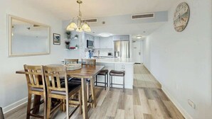 Een moderne keuken met witte kasten, een centraal eiland en een eetgedeelte met houten stoelen en een tafel.