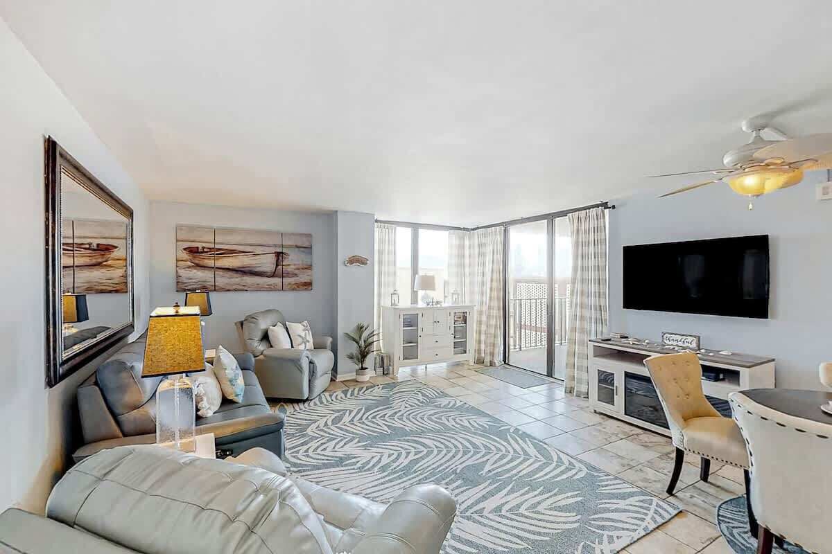 Ein modernes Wohnzimmer mit einer Couch, einem Couchtisch, einem Fernseher und einem großen Fenster.