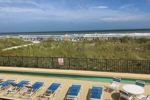 A beach view with a pool area, including lounge chairs and a table. - Sea Castle Unit A-3 Condo (North Myrtle Beach)