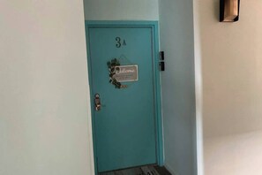 Una porta color aguamarina amb un rètol de 'Welcome' i el número '3A' a la part superior.