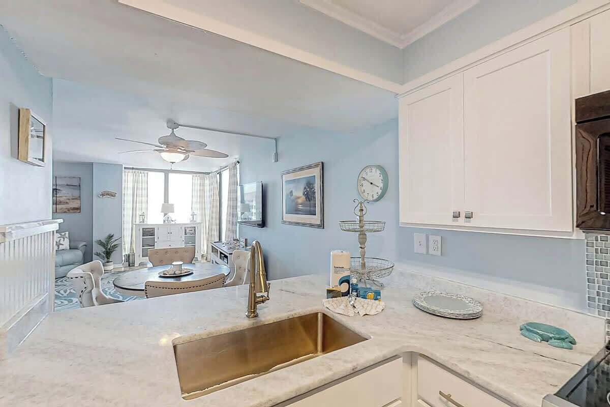 A kitchen with a sink, countertop, and cabinets. There is a dining area with a table and chairs.