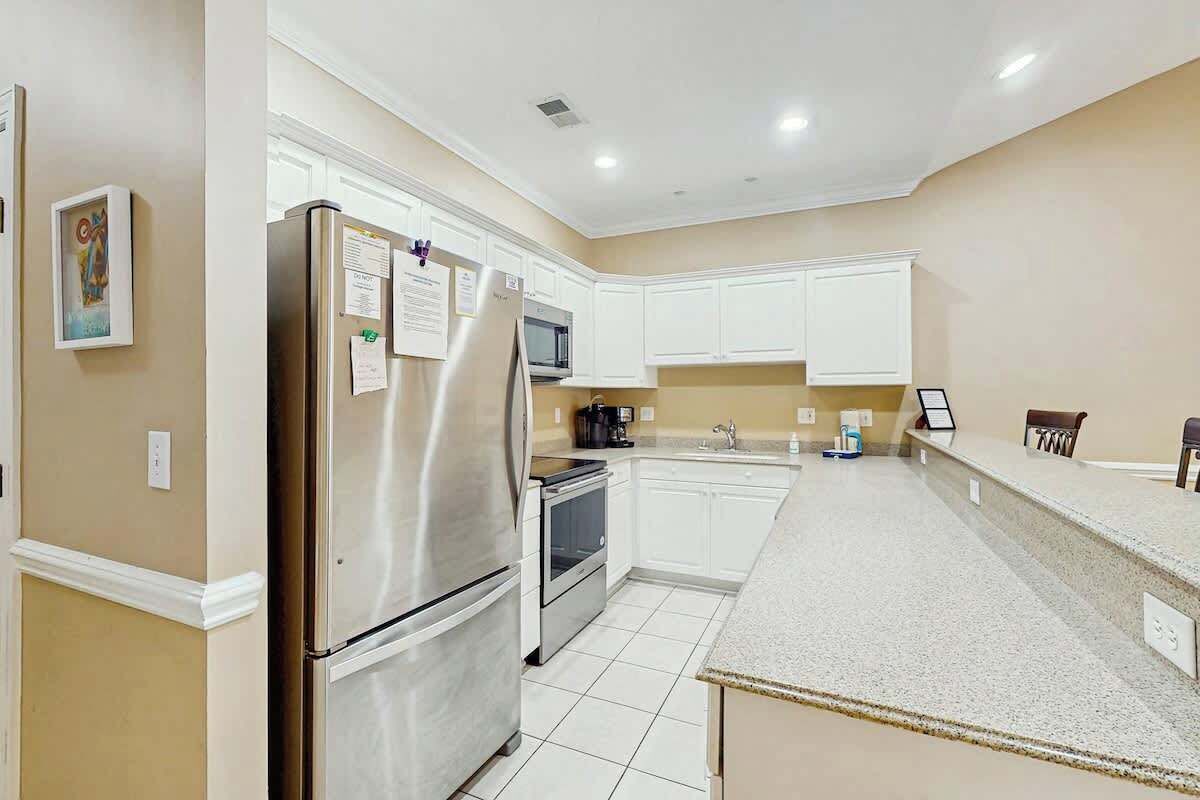 A modern kitchen with white cabinets, stainless steel appliances, and a granite countertop.
