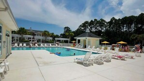 A swimming pool with lounge chairs and umbrellas, surrounded by a fence and trees. - Tupelo Bay, Unit 1514 (Murrells Inlet)
