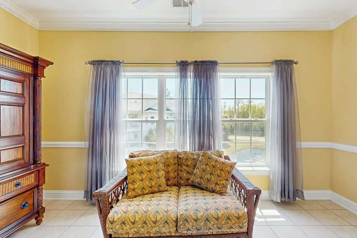 A room with a large window, a wooden chair with patterned cushions, and a wooden cabinet.