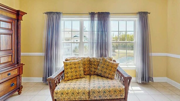 A room with a large window, a wooden chair with patterned cushions, and a wooden cabinet. - Tupelo Bay, Unit 1514 (Murrells Inlet)