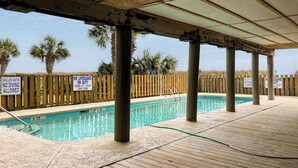 Ein Freibad mit Holzsäulen und einem Holzzaun. Schilder weisen auf flaches Wasser und das Verbot des Tauchens hin.