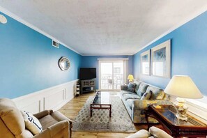 A living room with a sofa, armchair, coffee table, and a television. - Windy Village Unit C-2 (North Myrtle Beach)