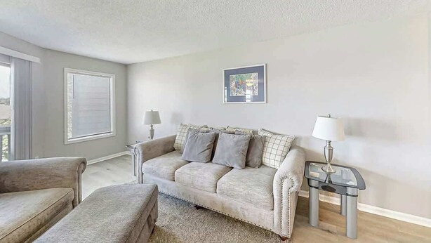 Ein Wohnzimmer mit einer Couch, einem Beistelltisch, einer Lampe und einem gerahmten Bild an der Wand.