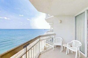 Ein Balkon mit Blick auf den Ozean, weiße Plastikstühle und ein 'NICHTRAUCHEN'-Schild.