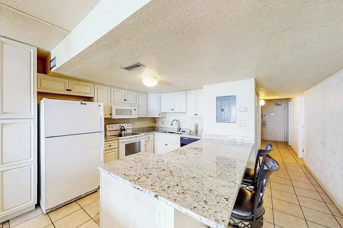 A kitchen with white cabinets, a granite countertop, and a refrigerator.