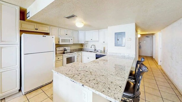 A kitchen with white cabinets, a granite countertop, and a refrigerator. - Water's Edge Resort 1002 (Murrells Inlet)