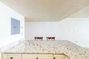 Eine Küche mit einer Granit-Arbeitsplatte, zwei Stühlen und einem blauen Schrank.