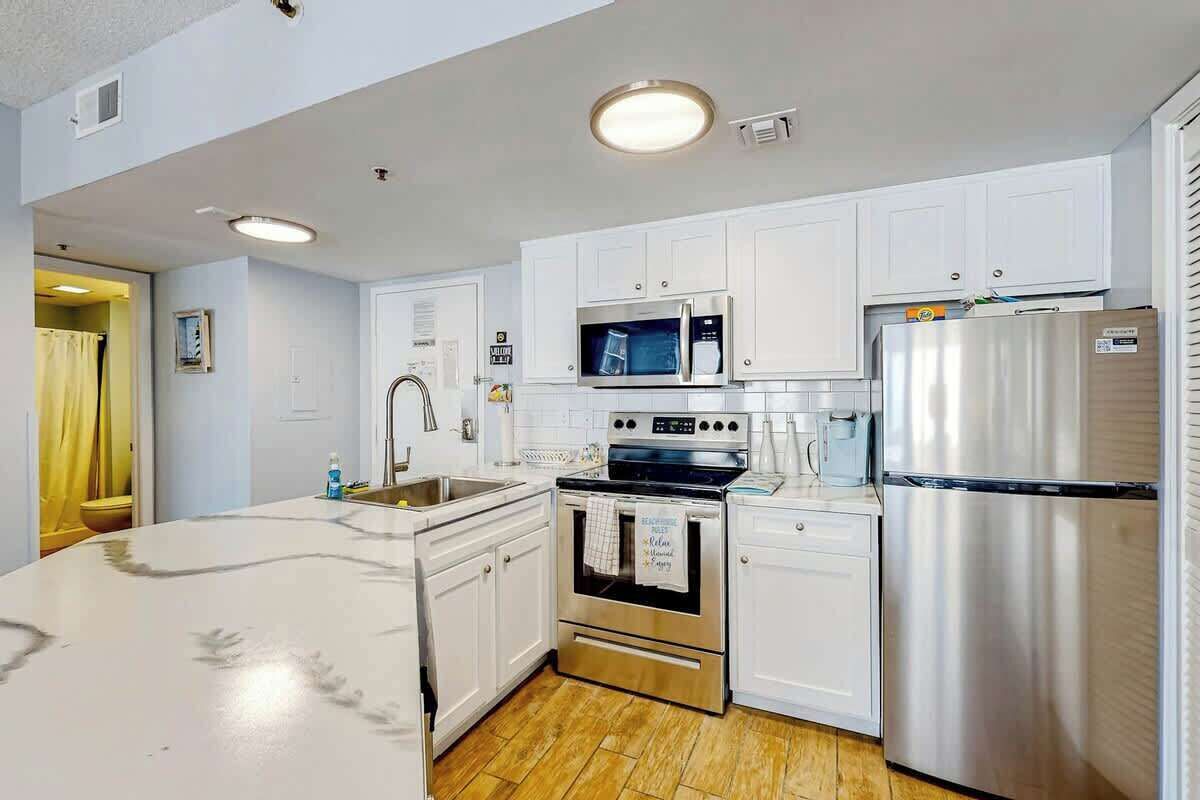 Una cocina moderna con armarios blancos, electrodomésticos de acero inoxidable y piso de madera.