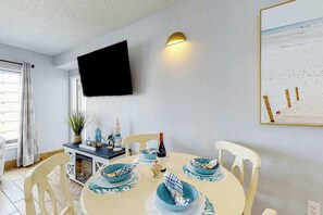 Ein Essbereich mit einem runden Tisch, Stühlen und einem an der Wand befestigten Fernseher.