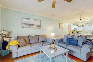 Ein Wohnzimmer mit grauem Sofa, einem Couchtisch und einem Gemälde an der Wand.