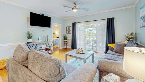 A living room with a sofa, coffee table, and a TV mounted on the wall. - Seas the Day at Magnolia Place (Myrtle Beach)