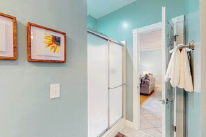 Ein Badezimmer mit Dusche, Handtuchhalter und einem gerahmten Bild an der Wand.