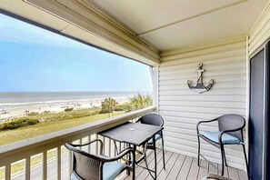 A balcony with a view of the beach, a table, two chairs, and an anchor decoration. - Ocean Forest Villas E-308 (Myrtle Beach)