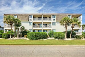 A multi-story residential building with balconies, palm trees, and a well-maintained lawn. - Ocean Forest Villas E-308 (Myrtle Beach)