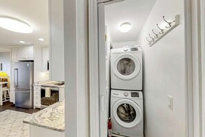 A modern kitchen with built-in appliances, including a refrigerator, oven, and a double-door washer and dryer. - Ocean Forest Villas E-308 (Myrtle Beach)