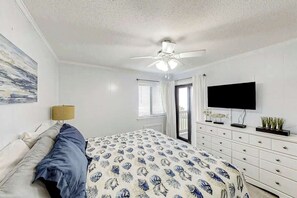 A bedroom with a bed, a ceiling fan, a TV, a dresser, and a window with blinds. - Ocean Forest Villas E-308 (Myrtle Beach)