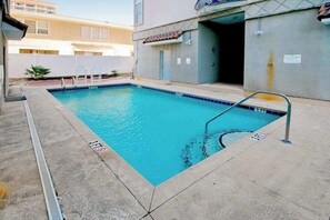 A rectangular pool with a metal ladder, surrounded by a concrete deck. - Tuscan Ocean Vista, Unit D (Myrtle Beach)