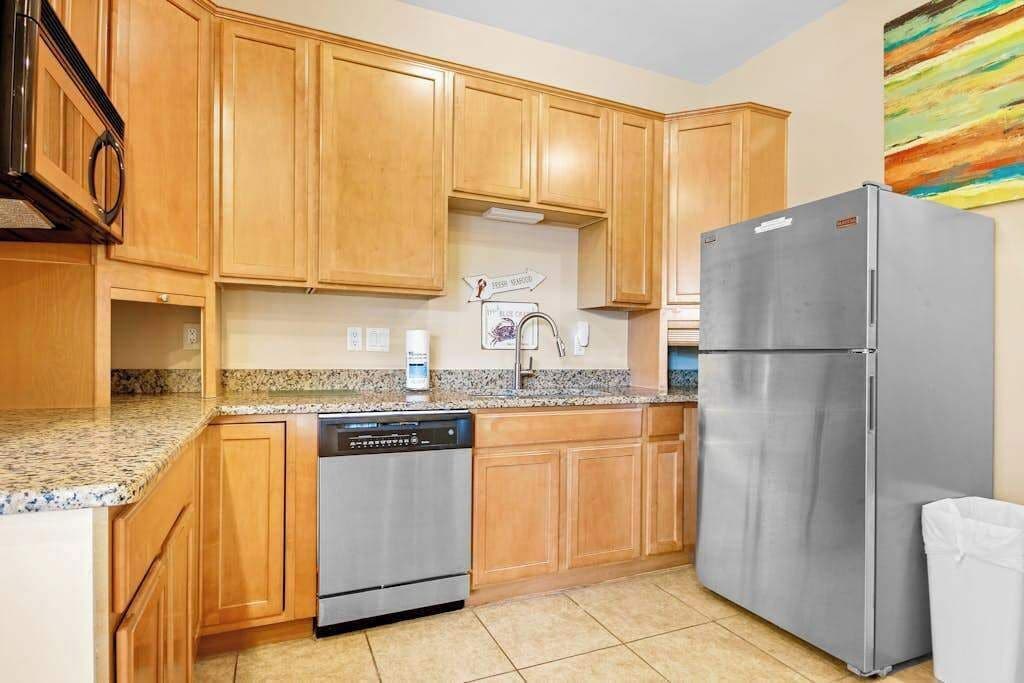Una cocina con armarios de madera, un refrigerador de acero inoxidable y un lavavajillas.