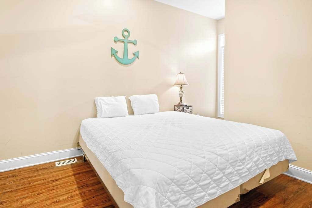 A bedroom with a bed, a nightstand, a lamp, and a wall-mounted anchor decoration.