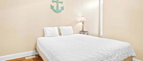 A bedroom with a bed, a nightstand, a lamp, and a wall-mounted anchor decoration.