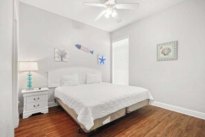 A bedroom with a bed, nightstand, and wall decorations. - Tuscan Ocean Vista, Unit D (Myrtle Beach)