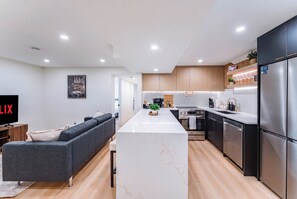 A modern kitchen with a central island, stainless steel appliances, and wooden cabinetry. - Luxury 3BR Guest Suite Near Downtown | Fast Wi-fi | Free Parking | Spa washrooms (Calgary)
