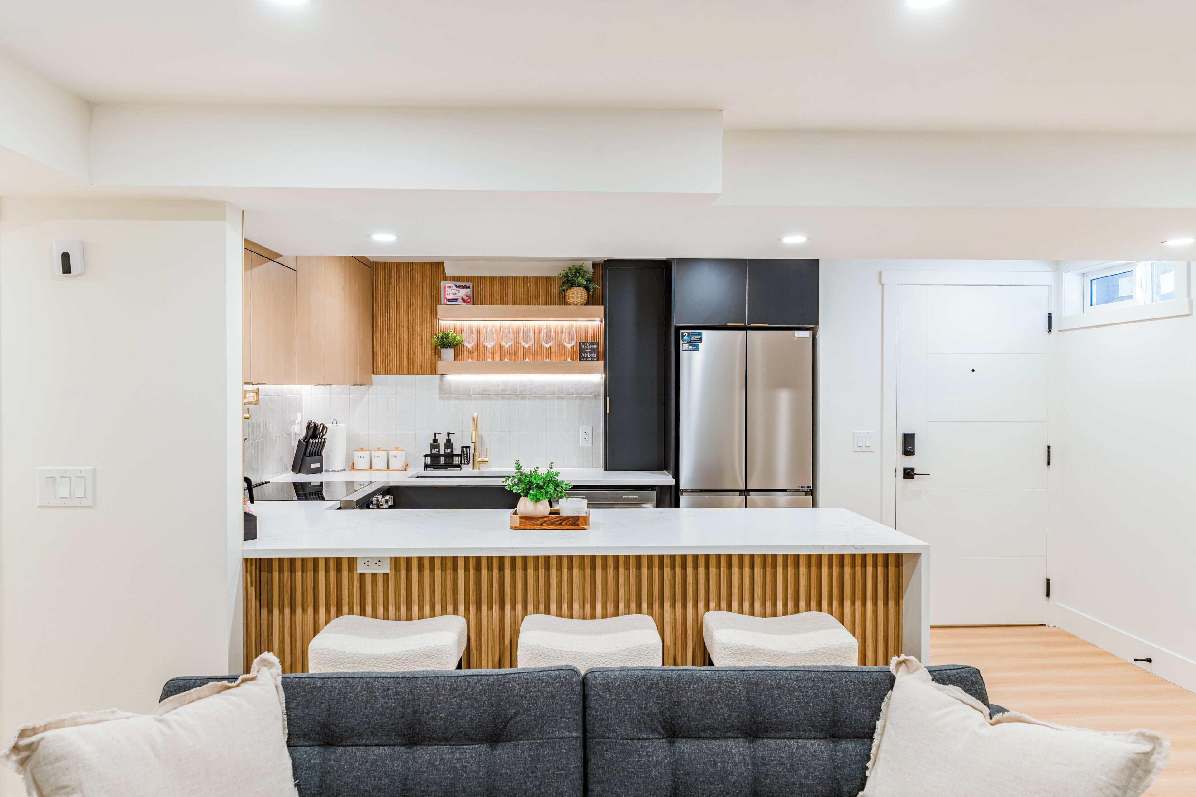 A modern kitchen with a central island, stainless steel appliances, and a wooden accent wall.