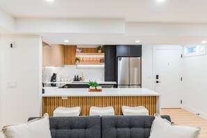 A modern kitchen with a central island, stainless steel appliances, and a wooden accent wall.
