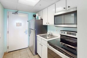 Eine kleine Küche mit Kühlschrank, Mikrowelle, Backofen und Spüle.