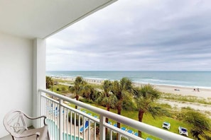 A balcony with a view of the beach, lounge chairs, and a pool. - Camelot by the Sea 0303 (Myrtle Beach)
