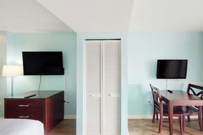 A room with a bed, a desk with a chair, a TV mounted on the wall, and a closet with sliding doors. - Camelot by the Sea 0303 (Myrtle Beach)
