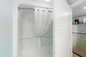 A bathroom with a shower, a glass door, and a coffee maker on the counter. - Camelot by the Sea 0303 (Myrtle Beach)