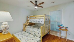 Ein Schlafraum mit Etagenbetten, Deckenventilator, Lampe und einem Fenster mit Jalousien.