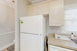 A kitchen with white cabinets, a white refrigerator, and a countertop with a kettle and a coffee maker. - Magnolia Escape Retreat (Myrtle Beach)